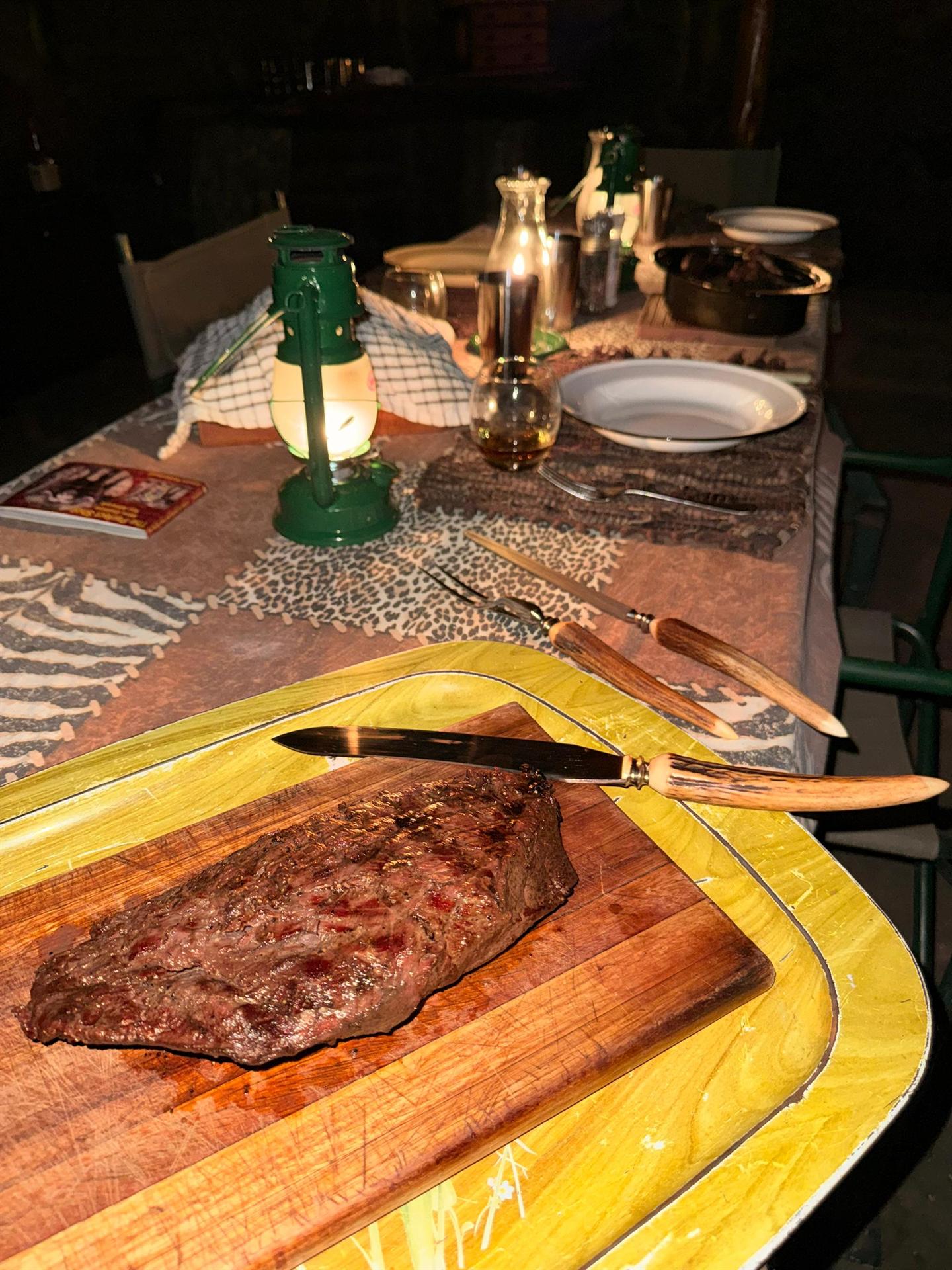 Game steak carved at the lantern-lit table
